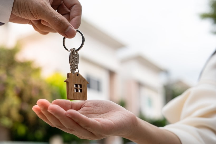 A man giving a woman keys to her new home after relocating using a relocation service provided by her employers